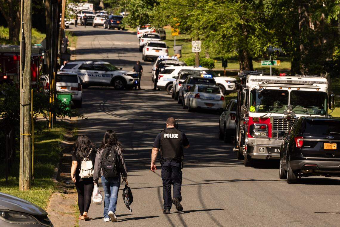 A CMPD officer, right, escorts two young girls trying to get home after school near the scene of a shootout on the 5000 block of Galway Drive in east Charlotte on Monday, April, 29, 2024.