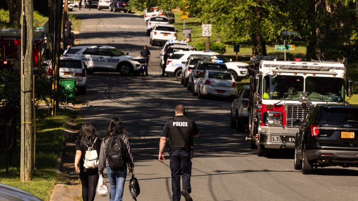 A CMPD officer, right, escorts two young girls trying to get home after school near the scene of a shootout on the 5000 block of Galway Drive in east Charlotte on Monday, April, 29, 2024.