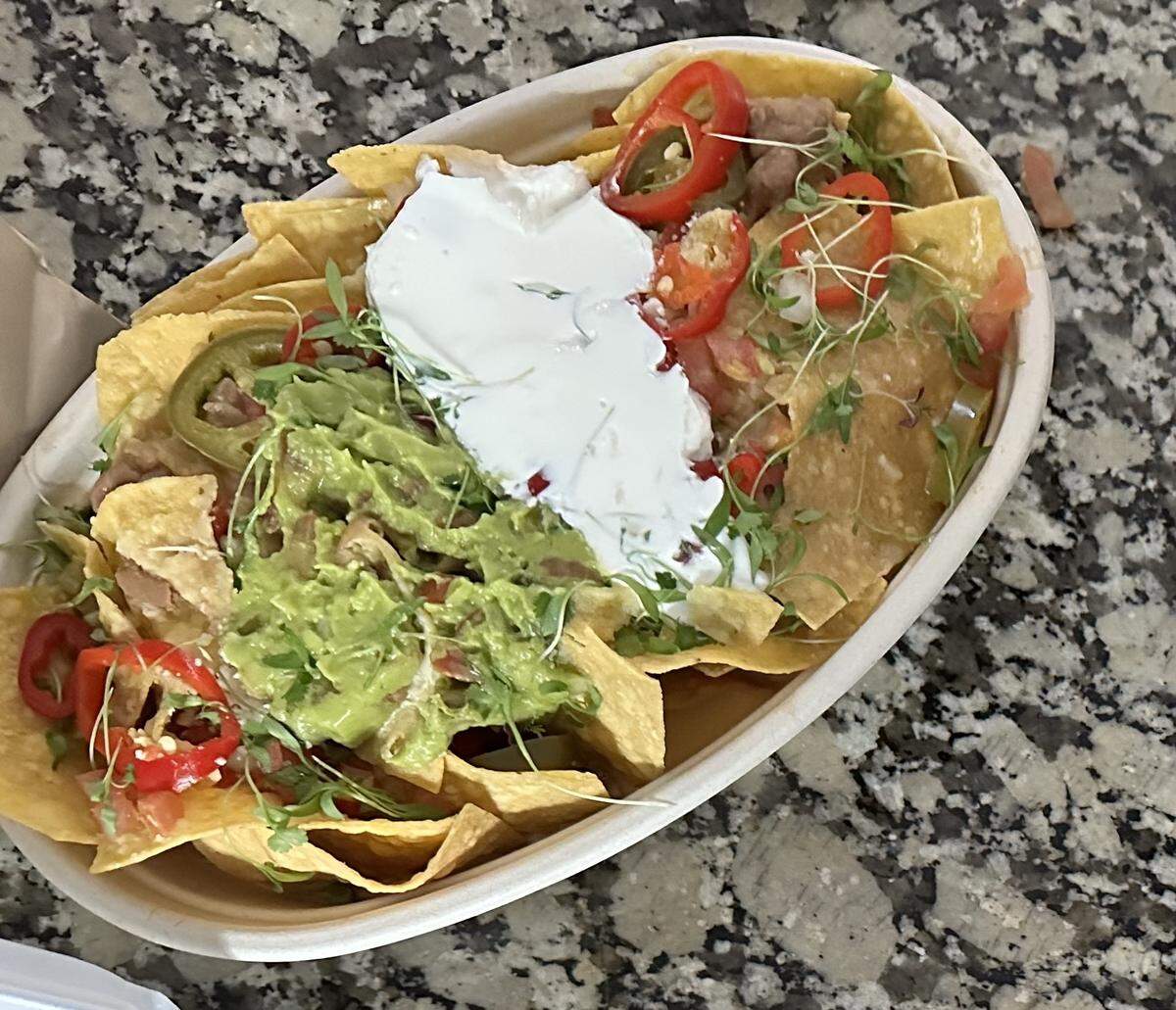 Que Fresa Taqueria + Bar’s vegetarian nachos are topped with whole pinto beans, pico de gallo, sour cream, guacamole, pickled chiles, queso dip and Cotija cheese.
