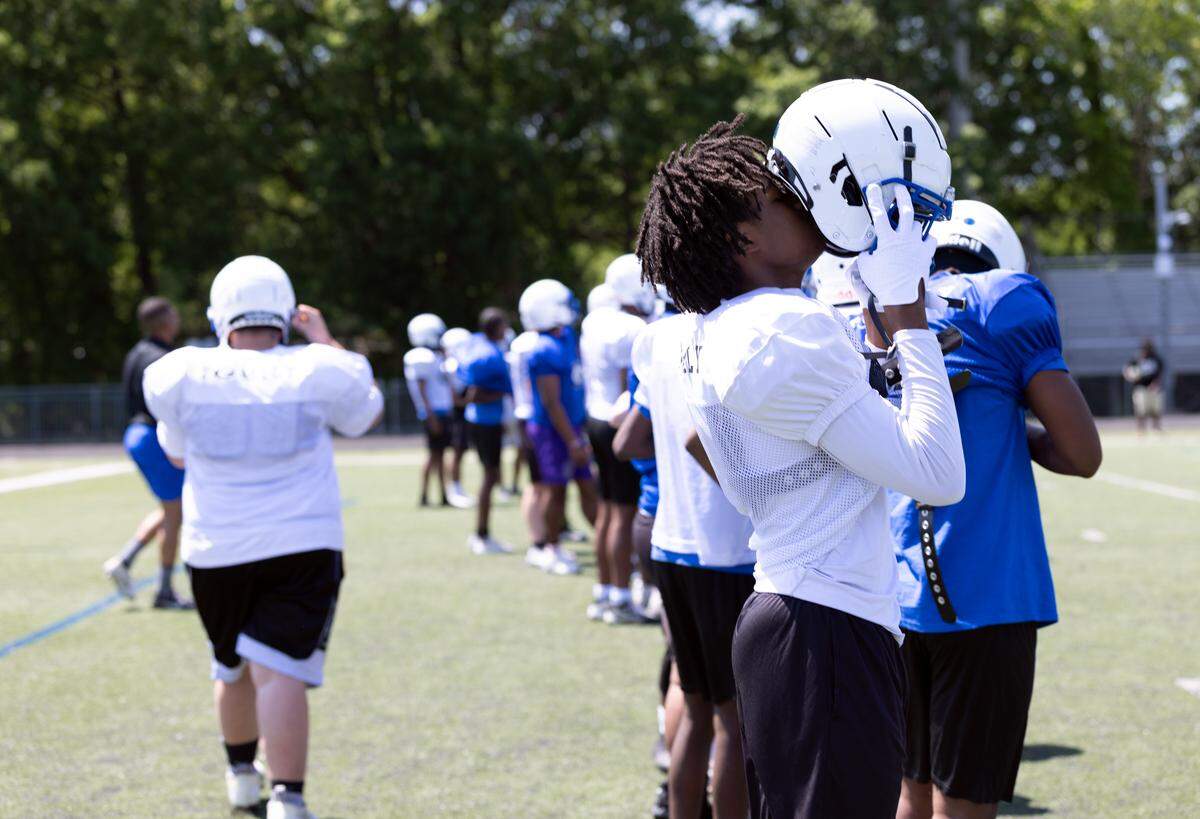 A Garinger High School football player adjusts his helmet during a spring workout session on the school’s practice field. While the program celebrated a significant breakthrough last fall by snapping a 48-game losing streak, the Wildcats are still contending with a 1-9 finish in 2025.