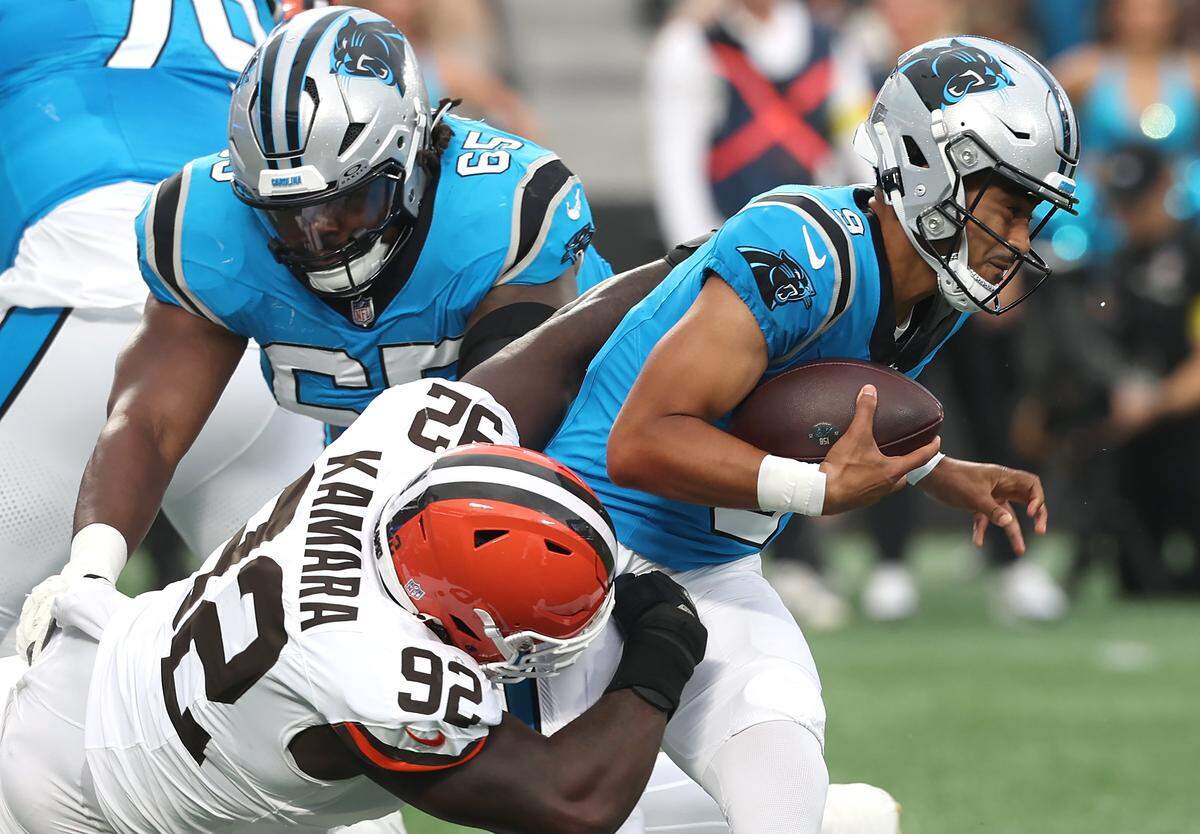 Carolina Panthers quarterback Bryce Young, right, fights to escape the grasp of Cleveland Browns defensive tackle Sam Kamara, center, during Friday’s game at Bank of America Stadium. Panthers guard Ja’Tyre Carter, left/top, attempts to assist Young’s escape.
