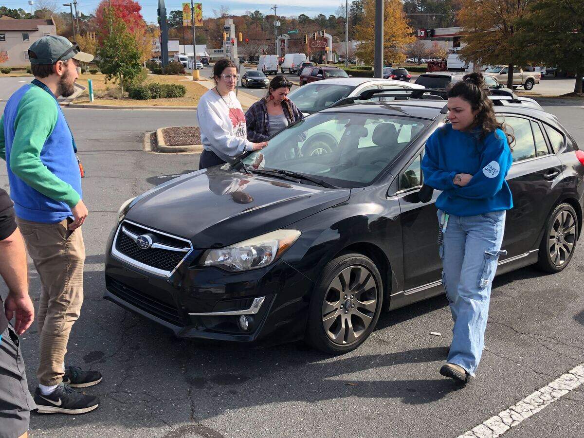 Local volunteers stand near the car of a Charlottean who was arrested by U.S. Customs and Border agents at the Eastway Crossing Shopping Center on Eastway Dr. In Charlotte, NC on Tuesday, November 18, 2025.
