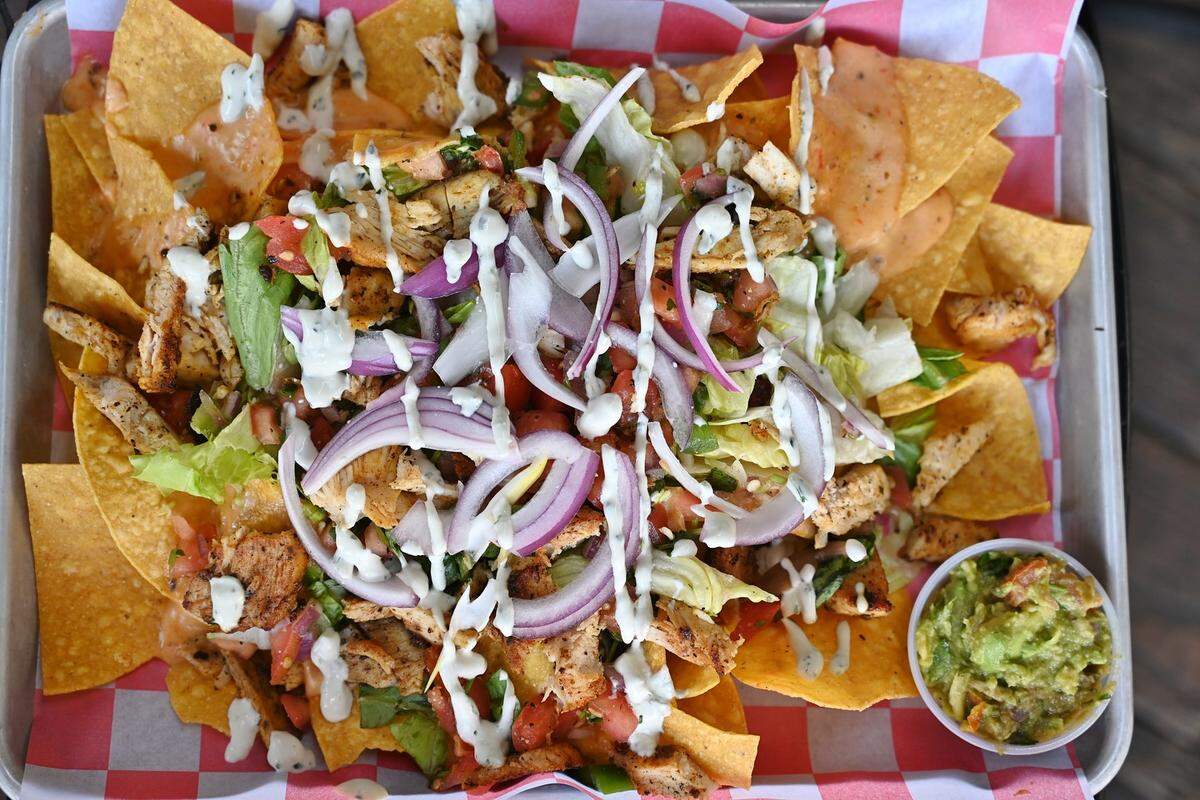 Angry Ale’s sheet pan nachos with roasted chicken, queso, pico de gallo, lettuce, tomato, jalapenos and more