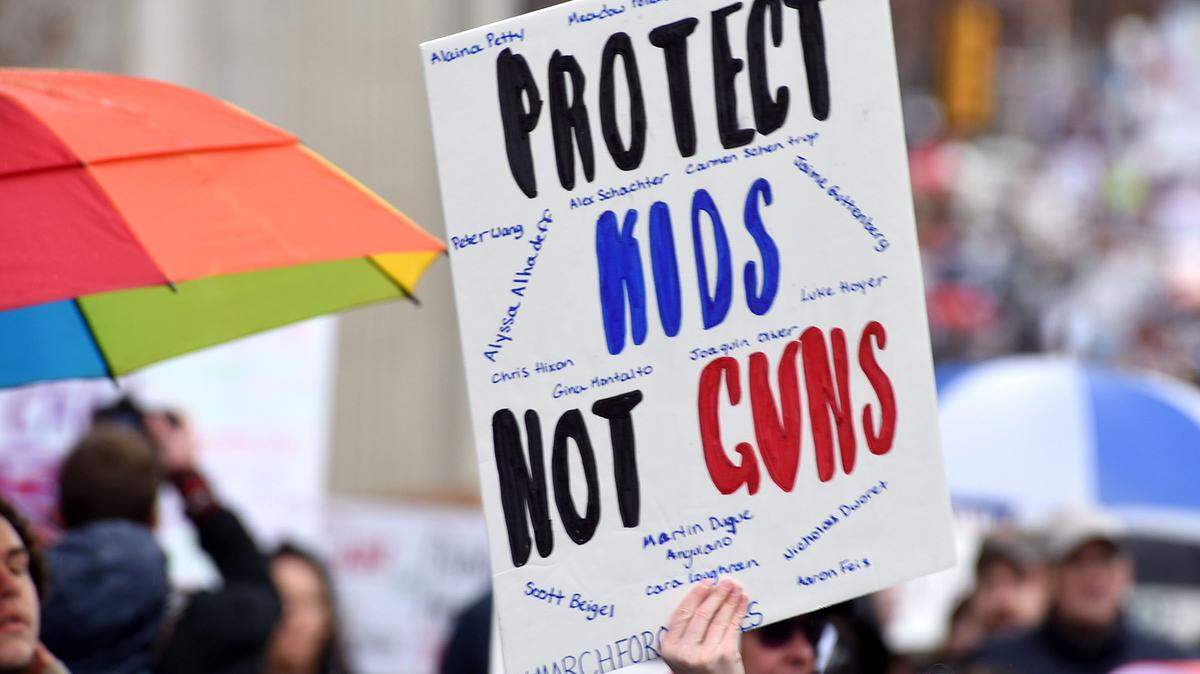 People hold signs during a Charlotte March For Our Lives student-led rally against gun violence. Teens from Charlotte area schools teamed up to lead the march, joined by a large crowd.