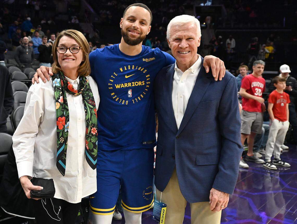 Golden State Warriors and former Davidson Wildcats star  Steph Curry, center, poses for a photograph with Cathy and Bob McKillop courtside at Spectrum Center in Charlotte, NC on Monday, March 3, 2025. 