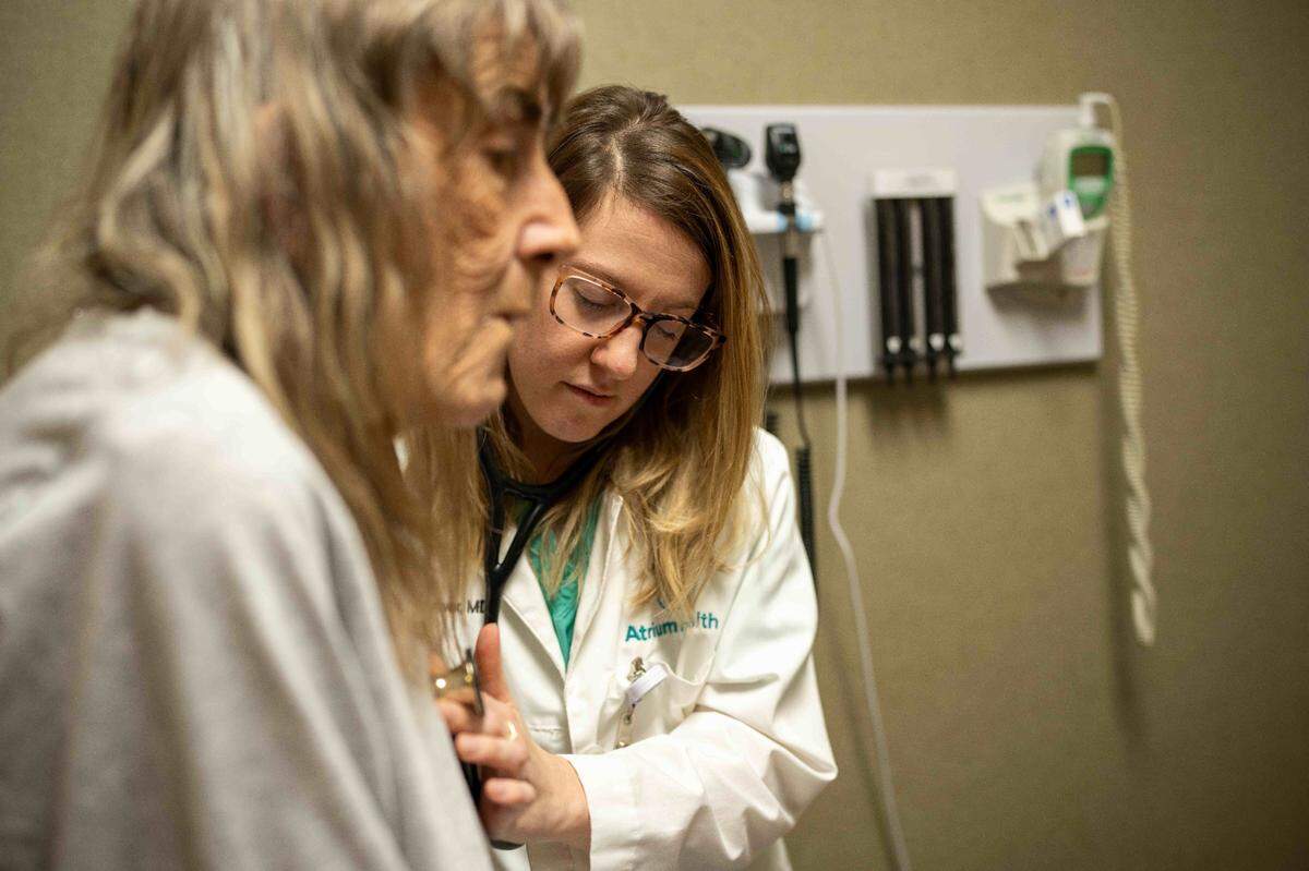 Dr. Paige Driver, of Atrium Health Primary Care Cabarrus Family Medicine, is one of the Atrium doctors using DAX Copilot, an AI-driven application on her phone that records patient-doctor interactions. That saves her time to focus more on patient interactions, Here, Driver listens to patient Sharon Vaughn’s heart rhythm for abnormalities, Friday, Oct. 6, 2023, in Concord.