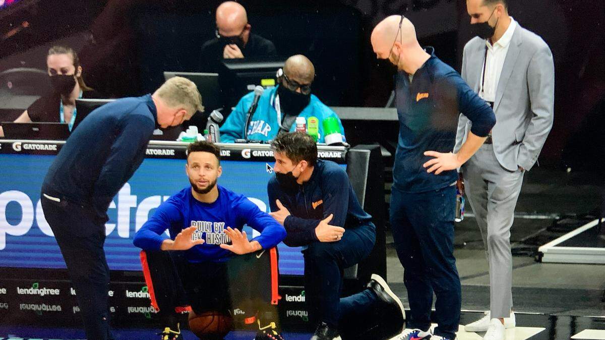 Golden State Warriors officials check on Stephen Curry (sitting on basketball), when he fell ill just before tip-off against the Charlotte Hornets at Spectrum Center. Announced as a starter, Curry instead went to the locker room just before the game began and did not play against his hometown team. Head coach Steve Kerr is on far left.