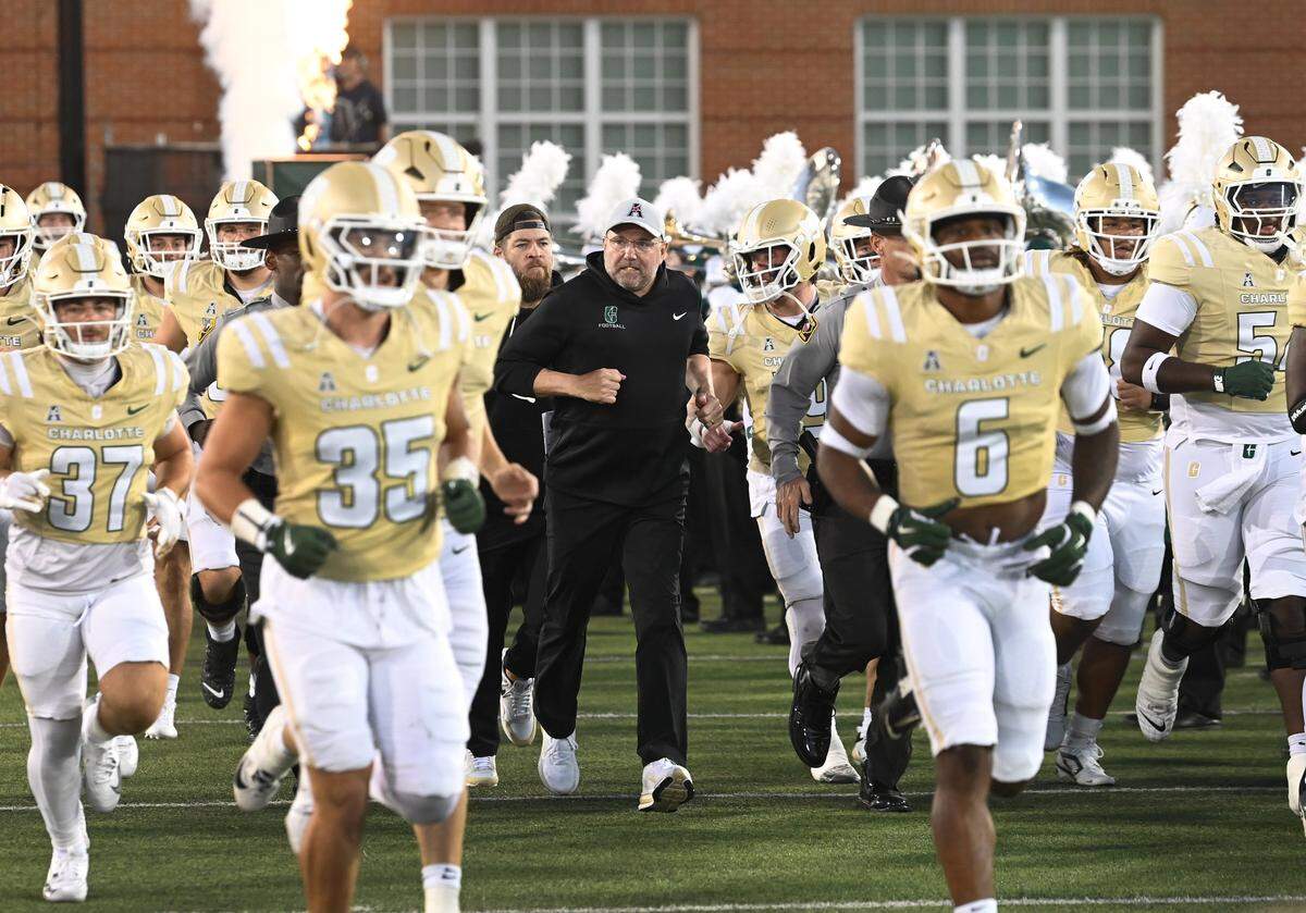 Charlotte 49ers head coach Tim Albin, center, runs onto the field with his team prior to action against the Rice Owls on Thursday, September 18, 2025 at Jerry Richardson Stadium in Charlotte, NC. Rice defeated Charlotte 28-17.