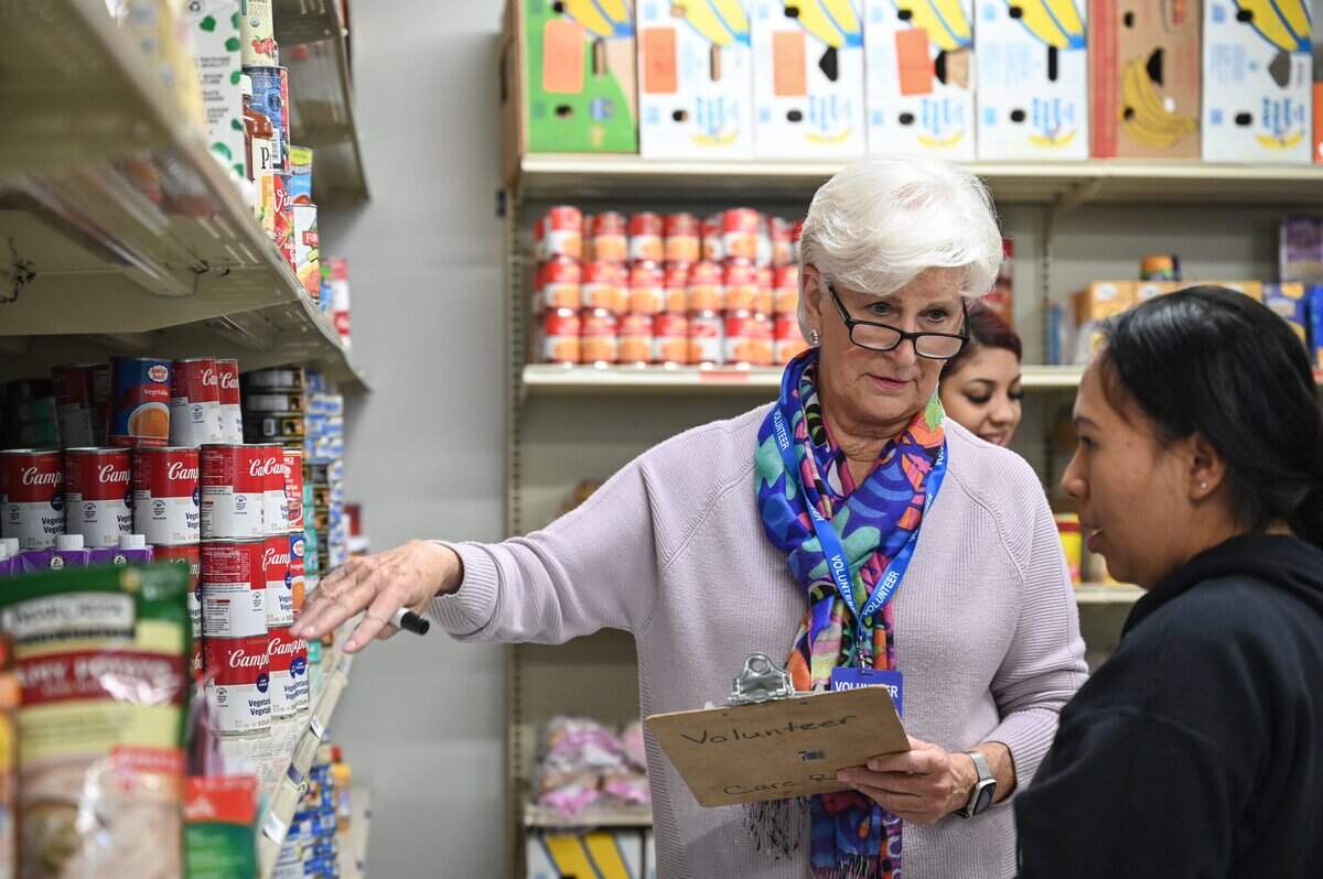 Carmen Odom, a former secretary of the North Carolina Department of Health and Human Services, volunteers by assisting residents in picking up food from the pantry at Care Ring in Charlotte.