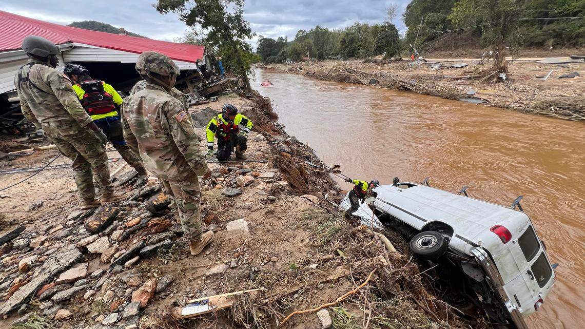A search and rescue team out of Atlantic Beach, N.C. examines a van swept into the river in Swannanoa, N.C. by flooding from Helene. They were assisting in the community, Sunday, Sept. 29, 2024.