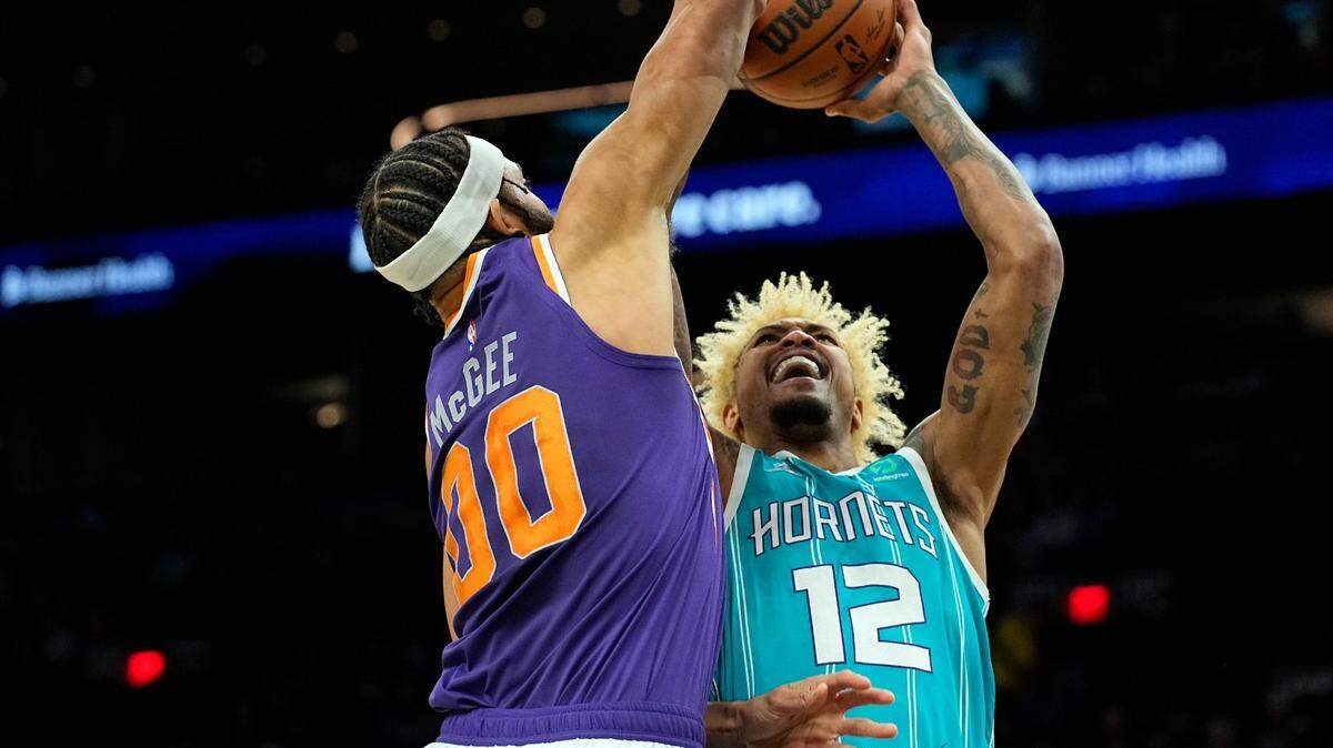 Charlotte Hornets guard Kelly Oubre Jr. (12) shoots over Phoenix Suns center JaVale McGee (00) during the first half of an NBA basketball game, Sunday, Dec. 19, 2021, in Phoenix. (AP Photo/Rick Scuteri)
