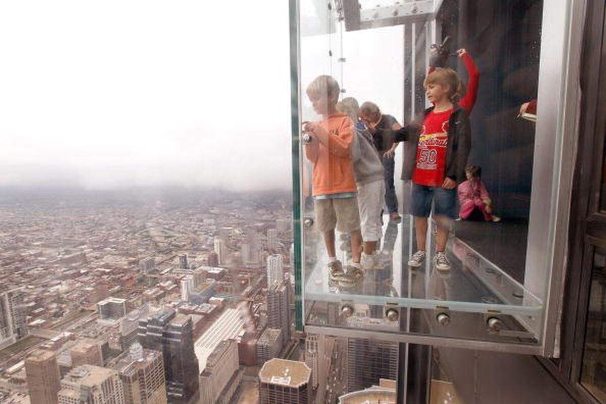 CHICAGO - JULY 01:  Children check out the view from the Ledge, a new glass cube that juts out from the 103rd floor Skydeck of the Sears Tower, during a media preview July 1, 2009 in Chicago, Illinois. The 1,353 foot high observatory will open to the public tomorrow.  (Photo by Scott Olson/Getty Images)