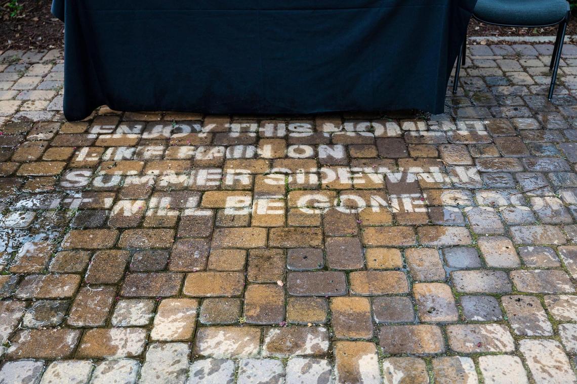 “Haiku: Enjoy This Moment”, a poem by Claudia Perry, is made visible by splashing water on a Charlotte walkway during a walking tour of the citywide art installation “Of Earth and Sky.” When dry, the poem is invisible. In order to achieve this illusion, the poem was stenciled onto the walkway using rain guard, which keeps the surface it is applied to dry, lasting up to six months.
