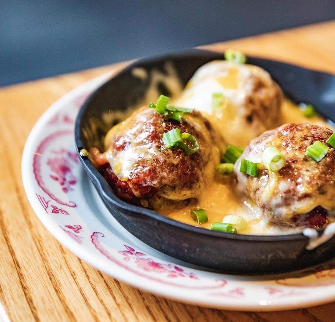 The Smoked Meatballs appetizer is topped with smoked jalapeño BBQ sauce, mixed melted cheese and green onion..