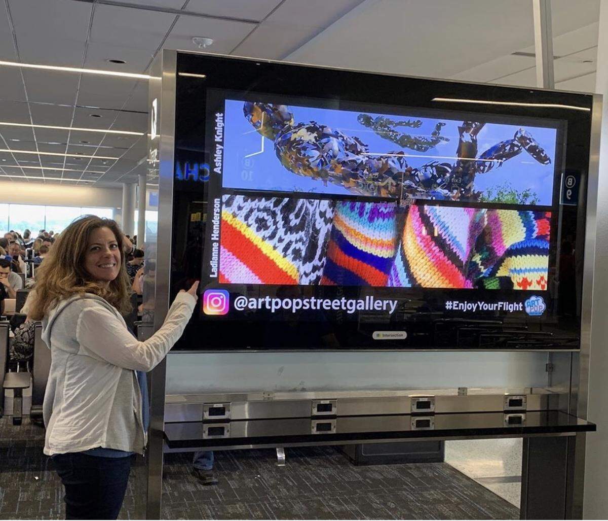 ArtPop founder Wendy Hickey stands in front of one of ArtPop’s charging stations at Charlotte-Douglas International Airport. It features artwork by Charlotte area artists Ladianne Henderson and Ashley Knight.