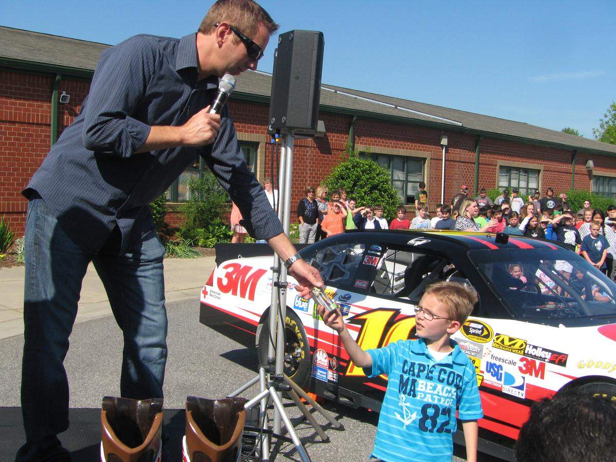 NASCAR driver Greg Biffle hands a student a model car for answering a question correctly when Biffle visited Lake Norman Elementary School on April 17.