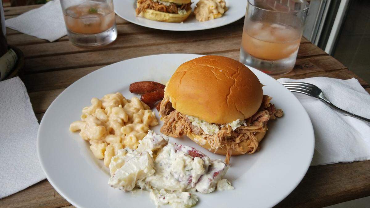 A plate with eastern North Carolina style pulled pork BBQ, mac and cheese, potato salad, and hushpuppies.