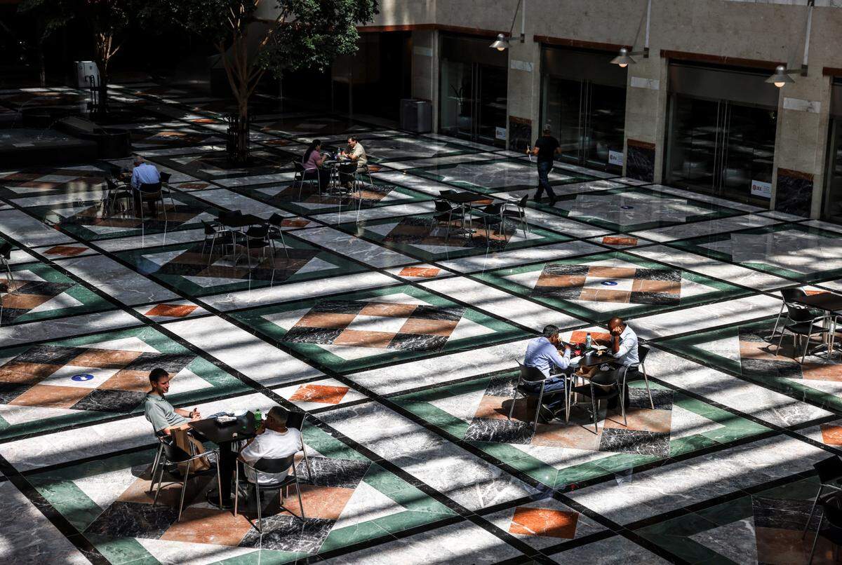 Sunlight filters across the floor as patrons gather at tables in Overstreet Mall in Charlotte, N.C., on Thursday, August 26, 2021. Overstreet Mall lost business when employers went remote in COVID. Now amid the delta variant, shops hope Wells Fargo, Bank of America will bring customers back.