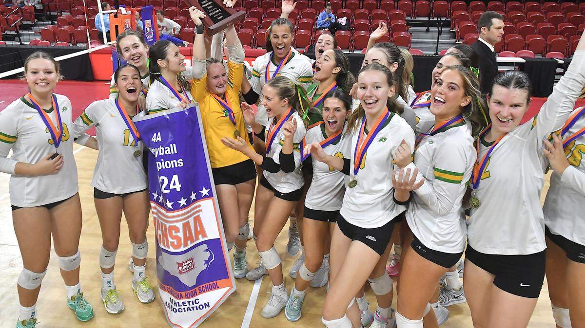 The Cardinal Gibbons Crusaders celebrate with the Championship trophy and banner after defeating Marvin Ridge in the NCHSAA 4A Volleyball Championship game. The Marvin Ridge Mavericks took on the Cardinal Gibbons Crusaders in the NCHSAA 4A Volleyball Championship match in Raleigh, N.C. on November 2, 2024.