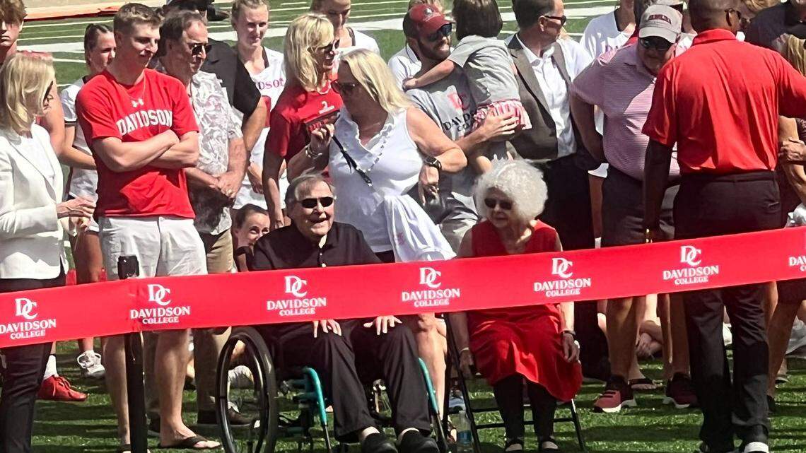 Beloved former Davidson College football coach David Fagg, seated with his wife, watches as a new field at the university is named in his honor.