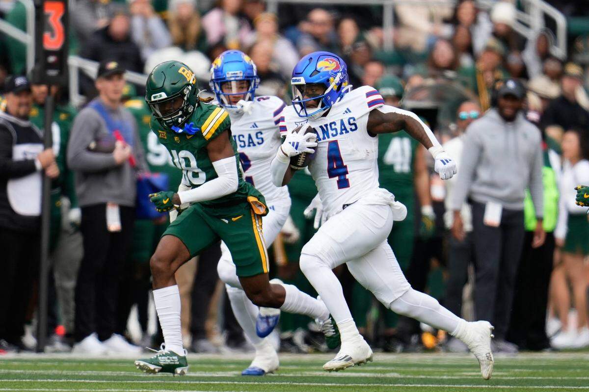 Nov 30, 2024; Waco, Texas, USA;  Kansas Jayhawks running back Devin Neal (4) runs with the ball as Baylor Bears cornerback Lorando Johnson (18) gives chaseduring the first half at McLane Stadium. Mandatory Credit: Chris Jones-Imagn Images