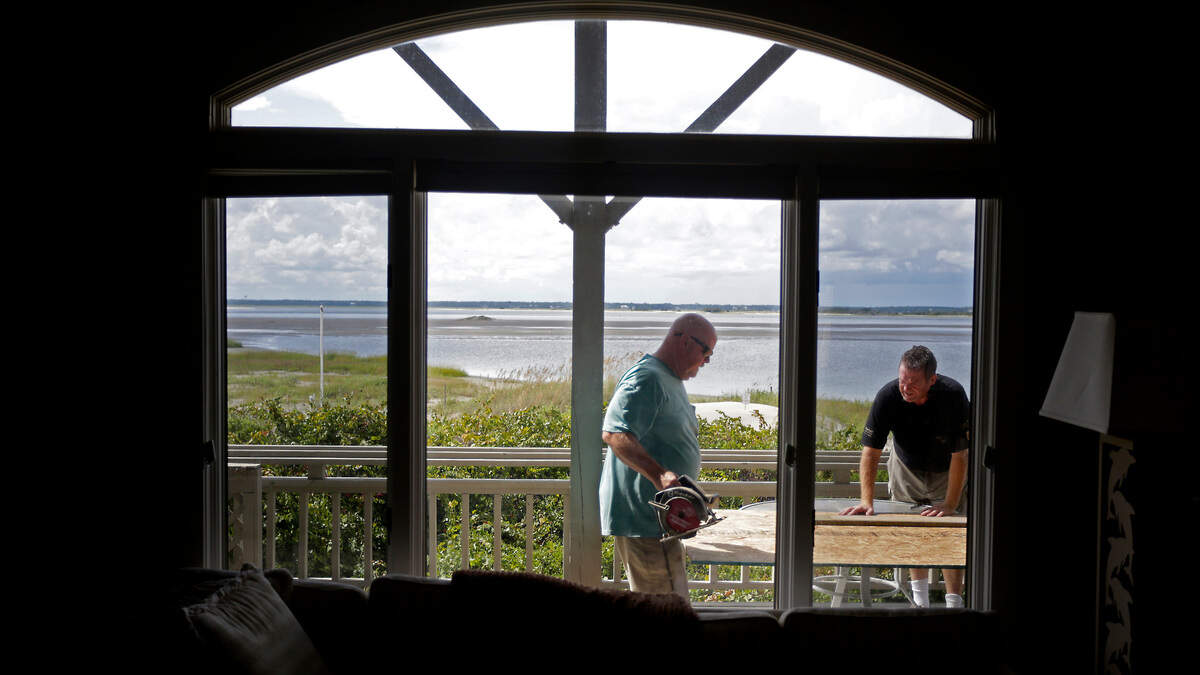Ralph Nelson, right, and David Gillespie prepare to cover windows of a home Tuesday in Emerald Isle, N.C., as they prepare for Hurricane Florence.