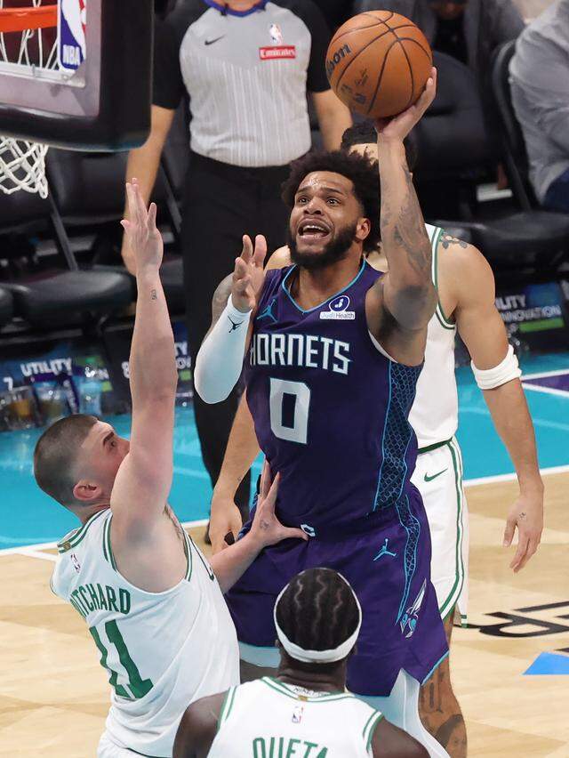 Charlotte Hornets forward Miles Bridges, center, drives to the basket for a shot over Boston Celtics guard Payton Pritchard, left, during action at Spectrum Center in Charlotte, NC on Sunday, March 29, 2026. The Celtics defeated the Hornets 114-99.
