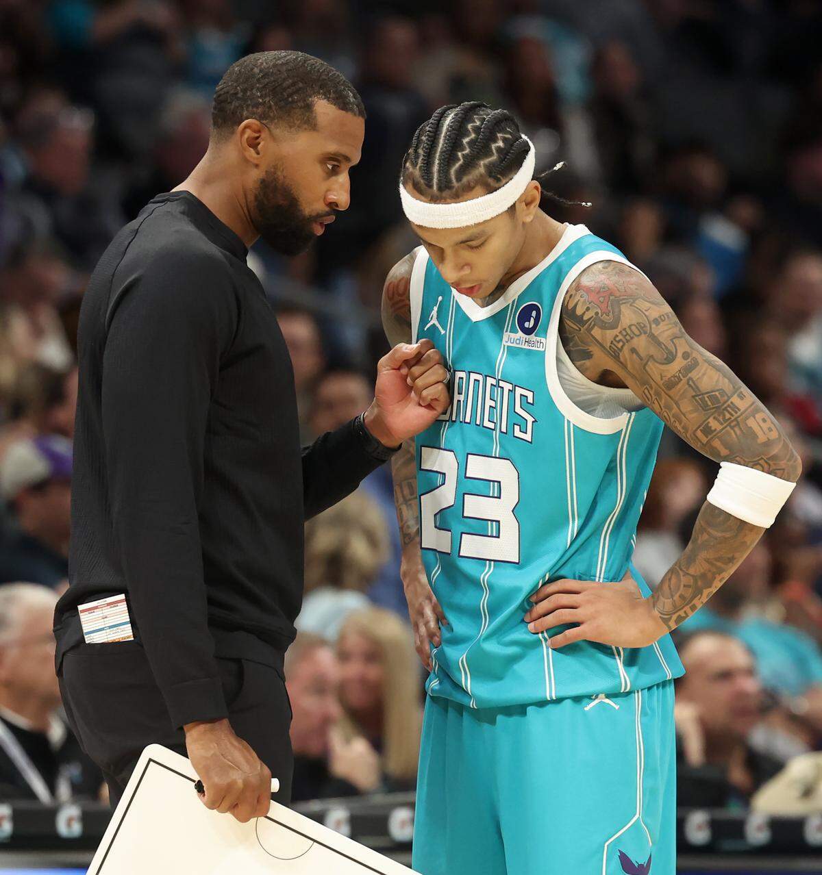 Charlotte Hornets head coach Charles Lee, left, speaks with guard Tre Mann during action against the Brooklyn Nets on Wednesday, Oct. 22, 2025 at Spectrum Center in Charlotte, North Carolina. The Hornets defeated the Brooklyn Nets 136-117.