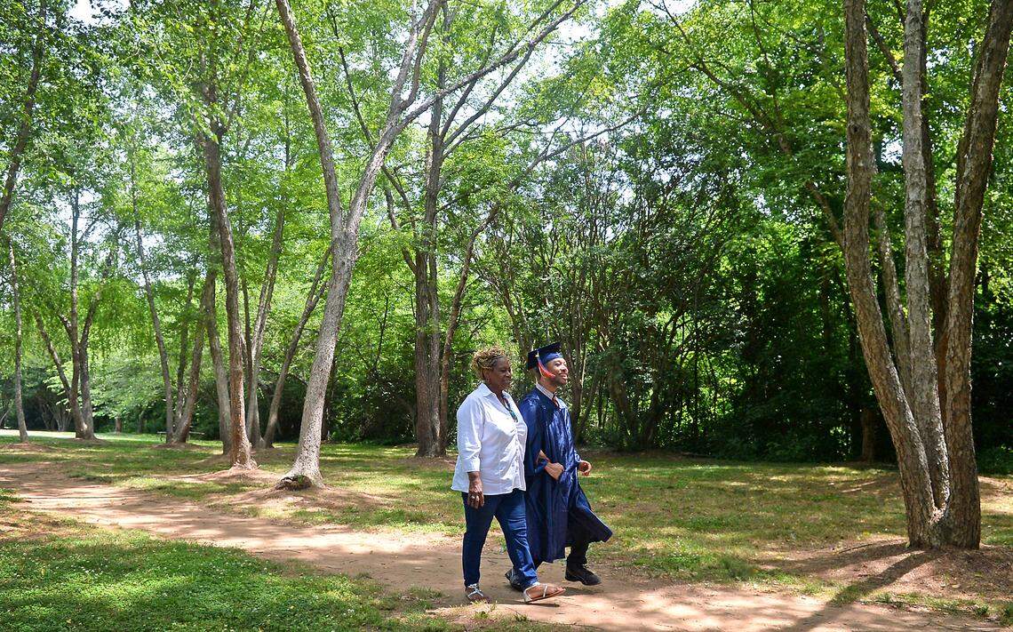Saundra Adams, left and Chancellor Lee Adams, right, walk down a path at Freedom Park in Charlotte on Monday. Chancellor Lee still has a walker, but he uses it less and less and plans to walk across the stage at graduation without it.