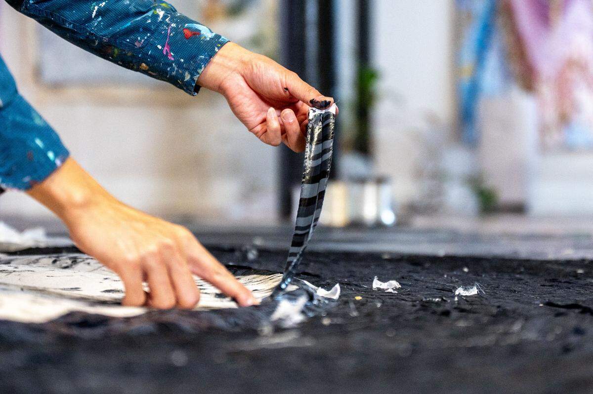 Kenny Nguyen, a Charlotte based artist, dips strips of silk into layers of paint before lying them onto of each other on a canvas in his Concord studio in Concord, NC, Tuesday August 1, 2025.