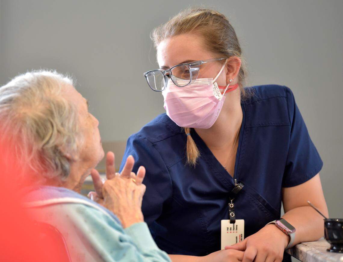 CNA Hannah Hefner, right, listens to resident Marlene Parker during lunch at the Abernethy Laurels nursing home.