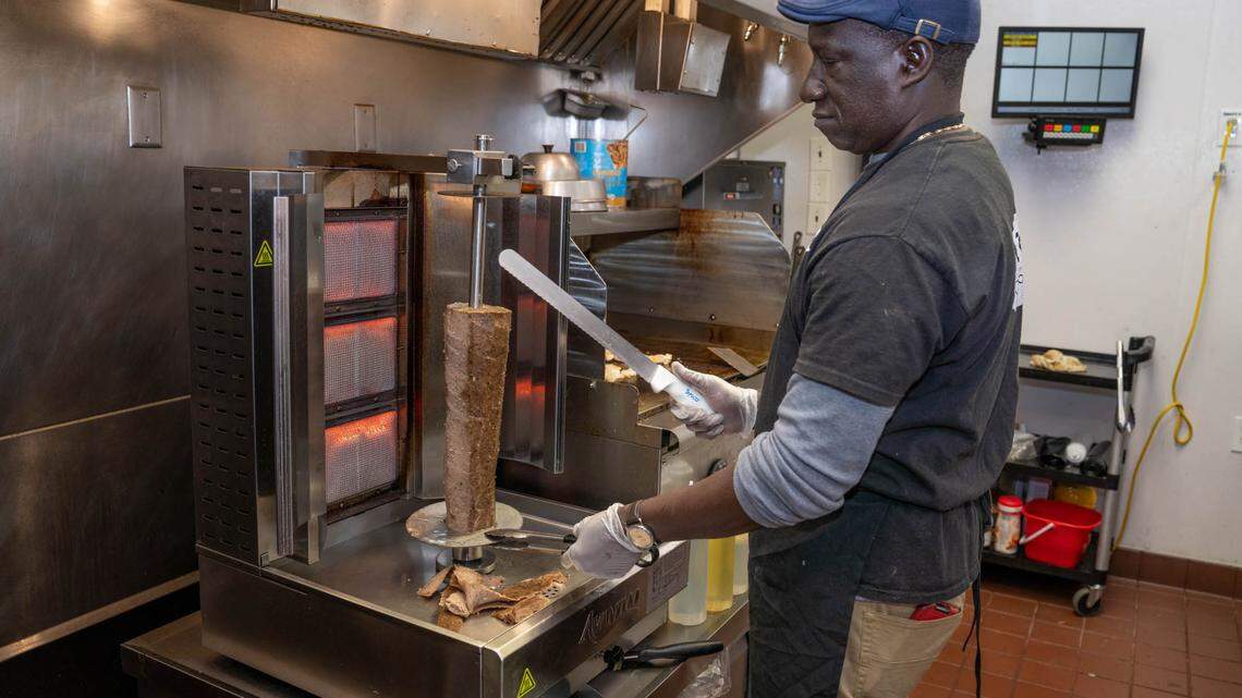 Mamadou Toure of Nick’s Gyros & Seafood carves meat for the gyro on a heated vertical rotisserie. 