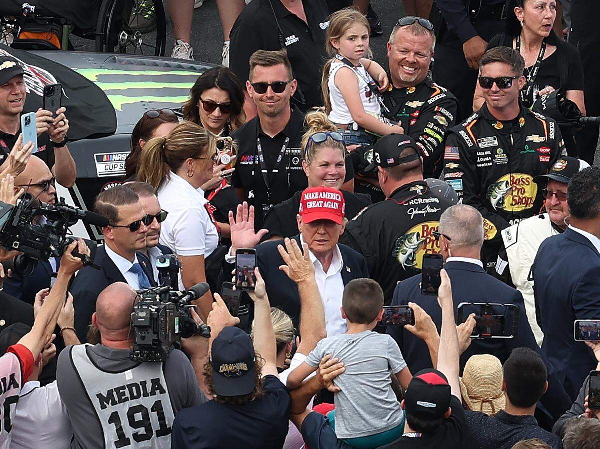 Former President Donald Trump, center, waves to fans along pit road at Charlotte Motor Speedway prior to the running of the Coca-Cola 600 in Concord on Sunday, May 26, 2024.