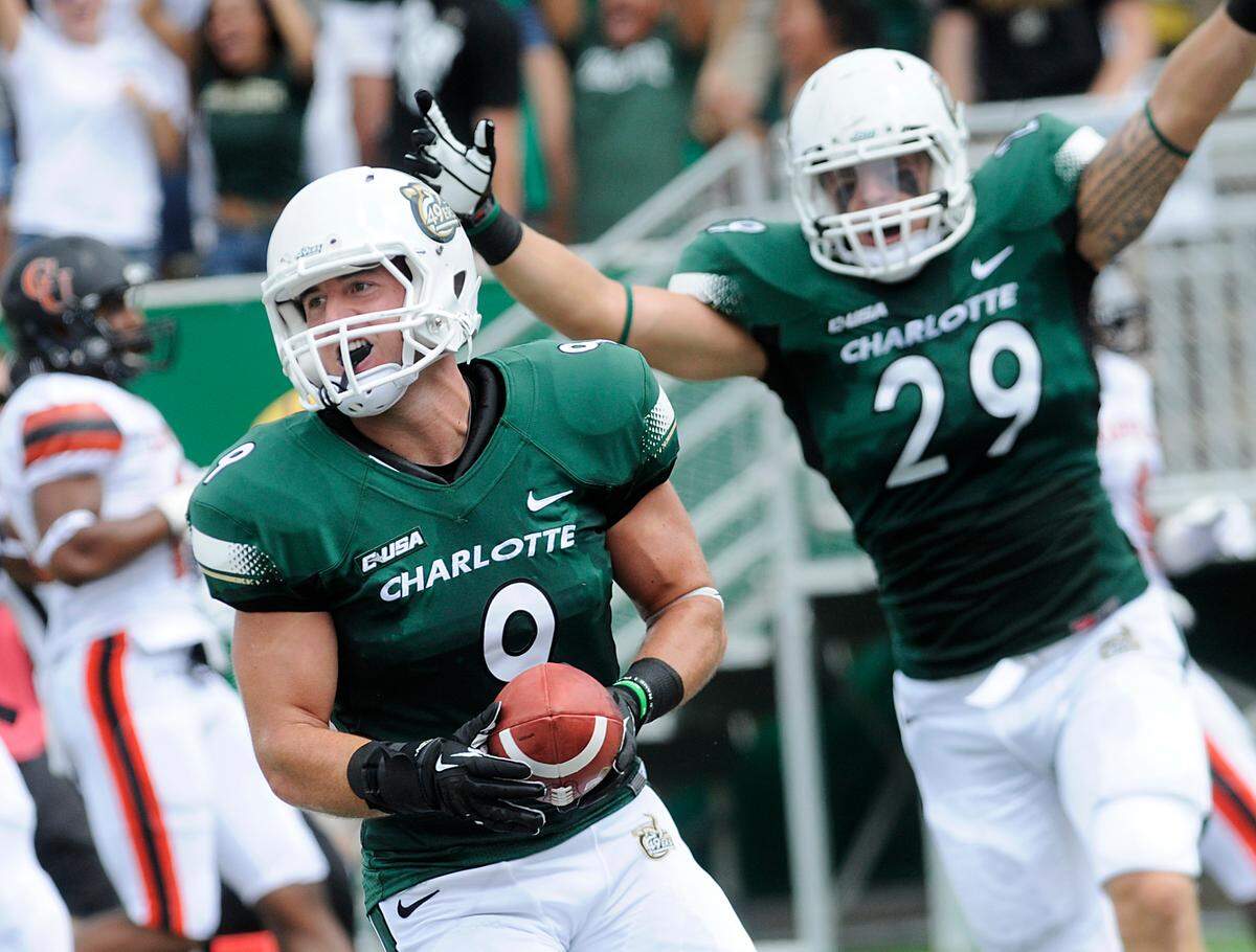 Mark Hogan, #9, a Charlotte 49er linebacker, intercepts a first half pass and returns it for the first touchdown of the game. Teammate #29 Micah Bryan rejoices in the score. The Charlotte 49ers stormed out to an early lead and pushed it to a 35-7 advantage at halftime over the Campbell Camels Saturday .