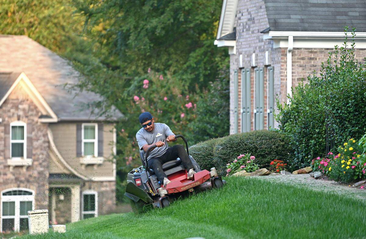 Santiago Lagunas mows a neighbor's yard.