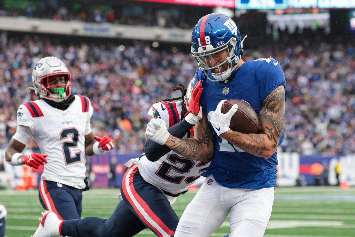 Nov 26, 2023; East Rutherford, New Jersey, USA; New York Giants wide receiver Isaiah Hodgins (18) scores a touchdown as New England Patriots safety Kyle Dugger (23) hits him during the first half  at MetLife Stadium. Mandatory Credit: Vincent Carchietta-USA TODAY Sports