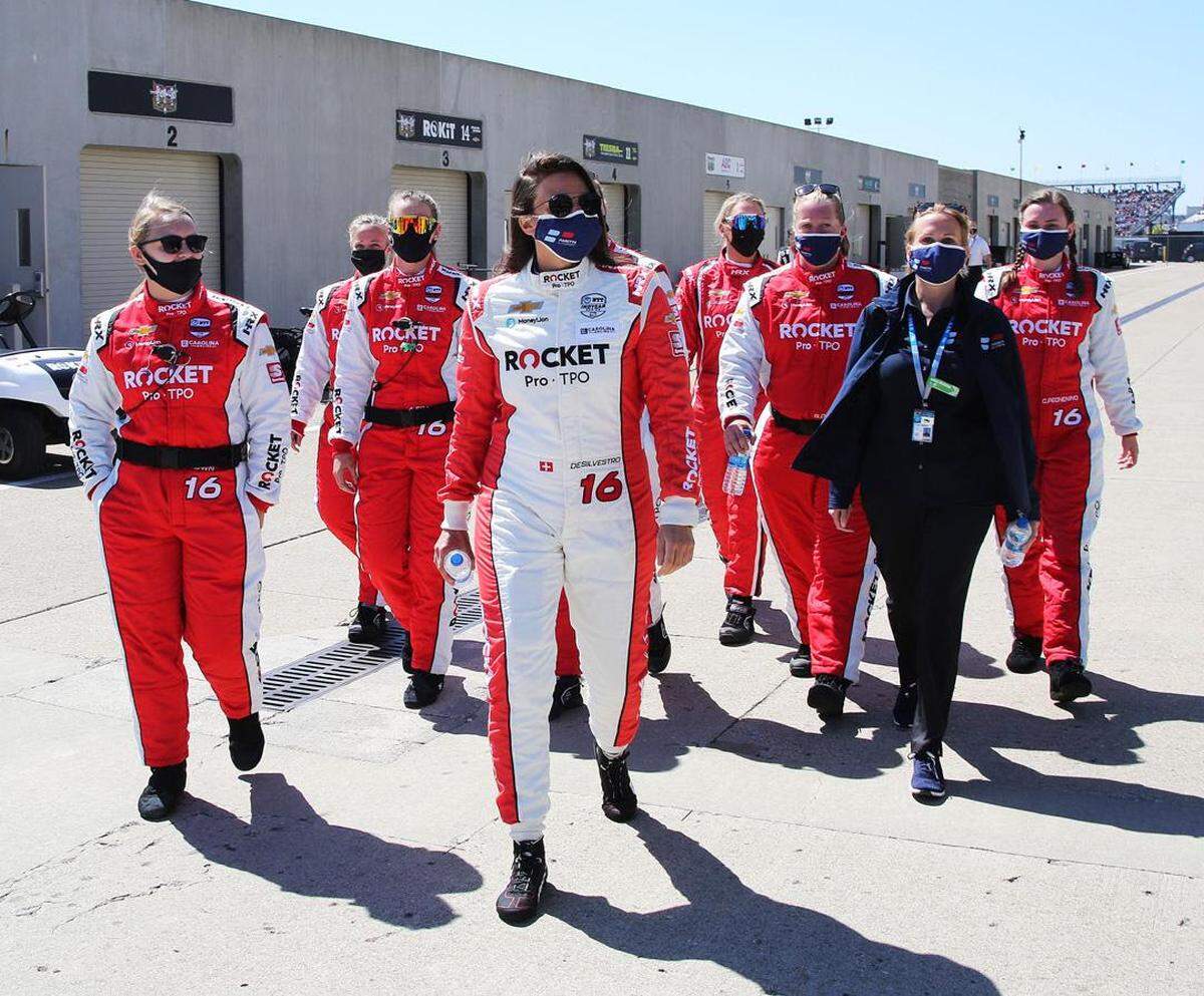 In this photo of the team walking down Gasoline Alley, Amanda Frayer is the team member in the orange-colored sunglasses (third from left). That’s IndyCar driver Simona De Silvestro in the foreground at the center of the frame.