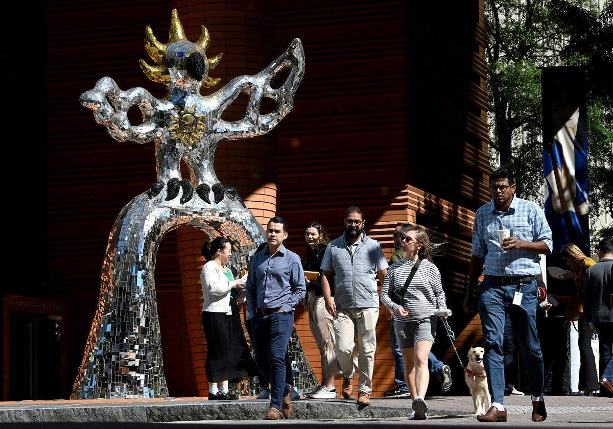 Uptown workers walk past the Firebird sculpture outside the Bechtler Museum. The statue is officially called: “Le Grand Oiseau de Feu Sur I’Arche,” or “ The Large Bird of Fire on the Arch” by artist Niki de Saint Phalle.