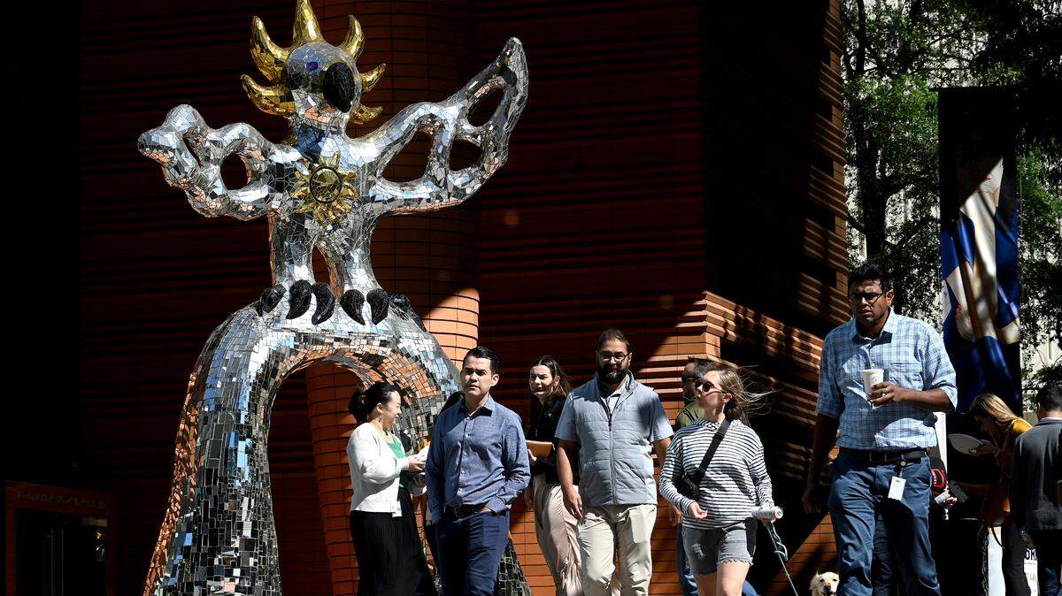 Uptown workers walk past the Firebird sculpture outside the Bechtler Museum of Modern Art on Thursday, October 10, 2024. October marks the 15th anniversary of one of the most popular sites in Charlotte having become popular for selfies and Instagram posts. The sculpture is officially called: “Le Grand Oiseau de Feu Sur I’Arche,” or “ The Large Bird of Fire on the Arch” by artist Niki de Saint Phalle. The sculpture is a combination of mirrors and colored glass.