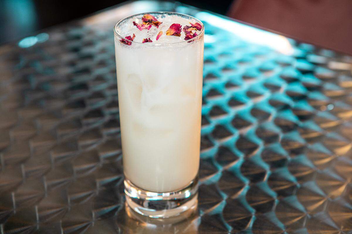 Belmont Cocktail Club’s Rose Gin Fizz has gin, cream, lemon juice, grapefruit juice, elderflower, rose, egg white, topped with soda and dried rose petals.