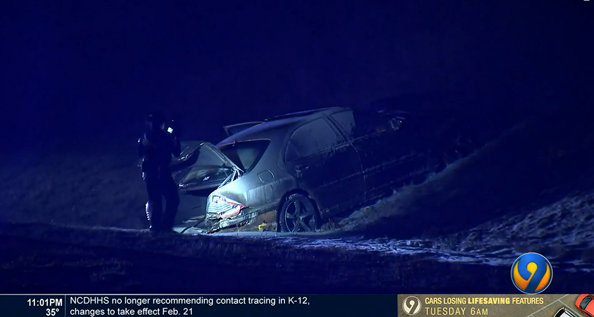 A police investigator takes photographs of the scene after a driver died when a vehicle crashed and burned Feb. 13, 2022, near the intersection of Interstate 485 and Mount Holly Road in northwest Charlotte. CMPD is investigating the crash as a homicide.