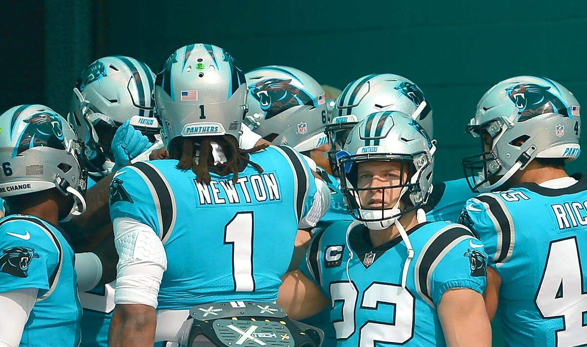 Carolina Panthers running back Christian McCaffrey, looks out onto the field as the team huddles around quarterback Cam Newton (1) prior to a game against the Miami Dolphins at Hard Rock Stadium in Miami Gardens, Fla. on Nov. 28, 2021.