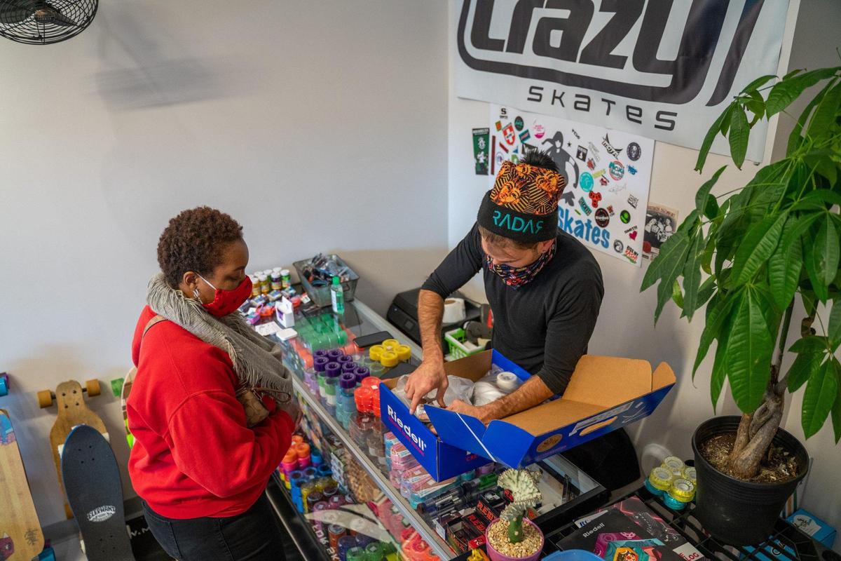Derby City Skates owner Nicholas Connell assists Jessica Reddick with her roller skates purchase.