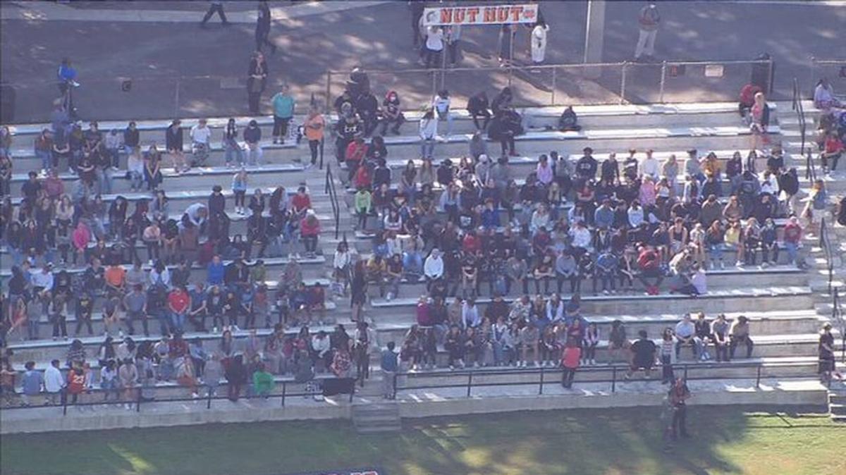 In this image from WSOC’s helicopter, students wait out an evacuation on the football stands at Northwest Cabarrus High School in Concord, NC, on Monday, September 19, 2022. School staff found a note with a bomb threat, forcing the evacuation.