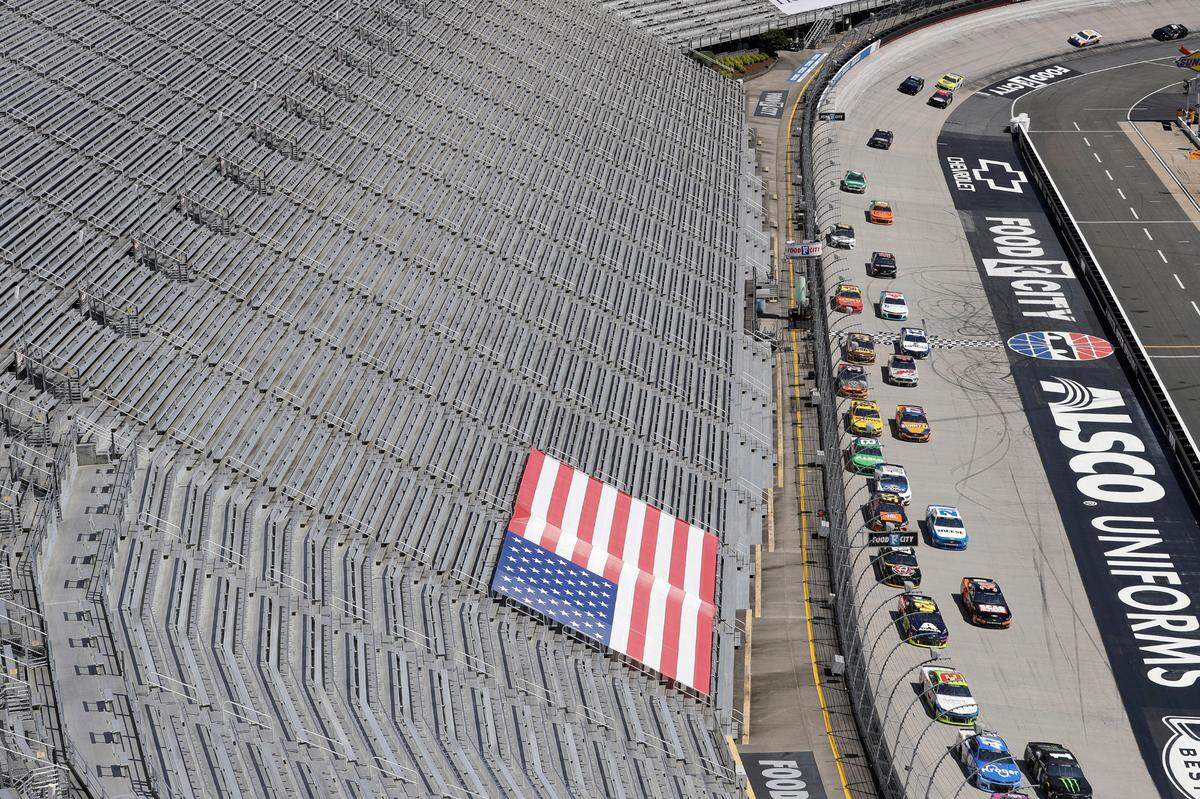 FILE - In this May 31, 2020, file photo, cars speed past empty stands during a NASCAR Cup Series auto race at Bristol Motor Speedway in Bristol, Tenn. Tennis and golf tournaments could be in real financial trouble if they are held without spectators because of the coronavirus pandemic. The biggest team leagues such as the NFL and NBA seem to be in good shape because they derive most of their money from TV contracts worth billions each season. NASCAR also relies mainly on broadcast rights fees. (AP Photo/Mark Humphrey, File)