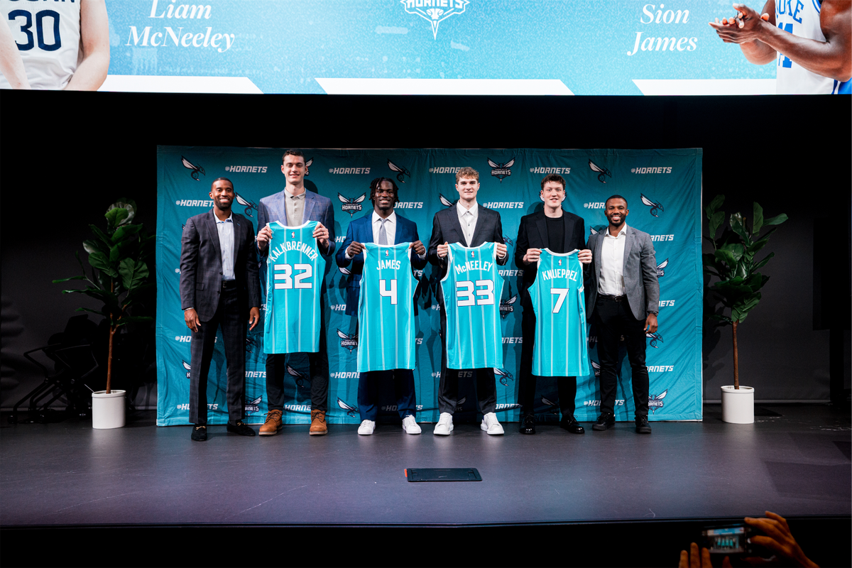 The Charlotte Hornets 2025 draft class posses alongside coach Charles Lee (left) and president of basketball operations Jeff Peterson.