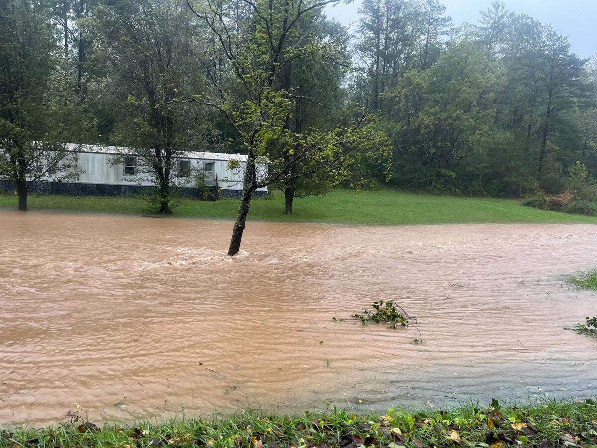 Water flows past a home in Weaverville, north of Asheville, in the morning on Friday, Sept. 27, 2024, after Helene struck.