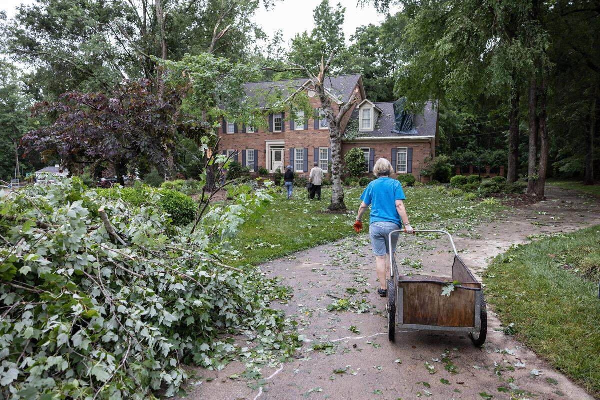 The Williams family cleans up tornado damage outside their home in Harrisburg, N.C., on Tuesday, May 24, 2022.