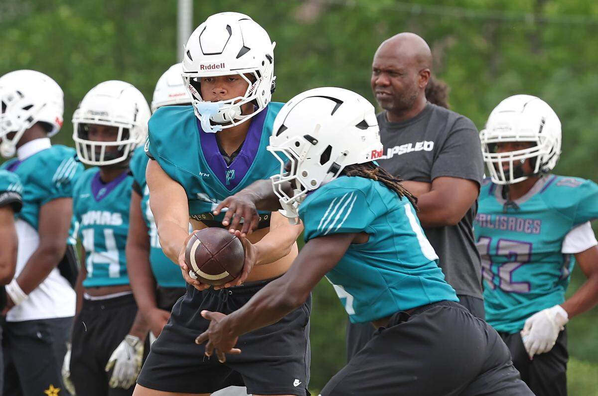 Palisades Pumas quarterback Cole Hough, center, hands the ball off during a spring workout on Thursday, April 30, 2026. Palisades is going for its third straight winning season and wants to jump into the upper echelon of Charlotte teams.