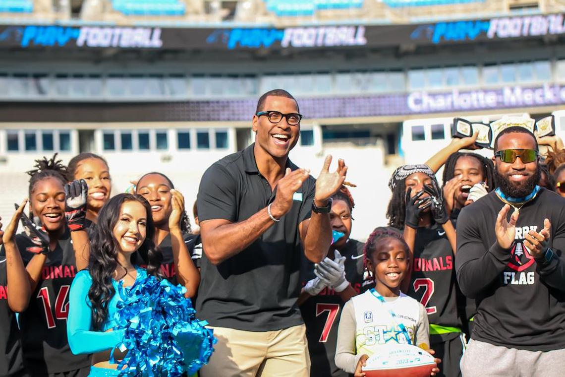 NFL Legend Mike Rucker celebrates with flag football teams at Bank of America Stadium in May 2023 to punctuate the second season of the Charlotte-Mecklenburg Schools girls’ flag football championship.